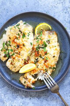 two pieces of chicken on a plate with lemon wedges and garnishes