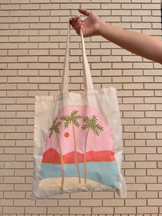 a person is holding a bag with palm trees on the beach in front of a brick wall