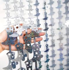 a person is holding up some silver and blue stars in front of a white background