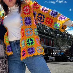 two women standing next to each other wearing crocheted grannys and sweaters