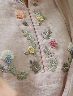 a close up of a person wearing a sweater with flowers on it and pearls around the neck