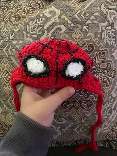 someone is holding up a crocheted spiderman hat