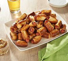 a white plate topped with lots of sausages next to a glass of orange juice