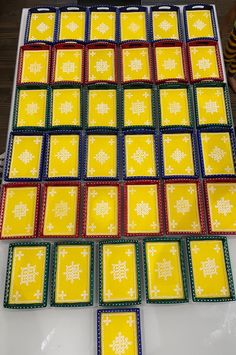 a table topped with lots of yellow and red squares covered in snowflakes on top of white tiles