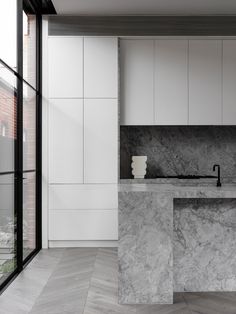 a kitchen with marble counter tops and white cabinets, along with an open floor plan