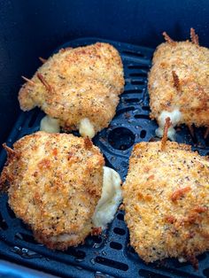 four chicken patties are cooking in an air frying pan with cheese on top