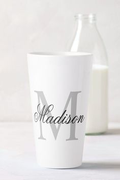 a white cup with the word madison written on it next to a bottle of milk