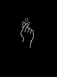 a hand holding a heart in the middle of it's fingers on a black background