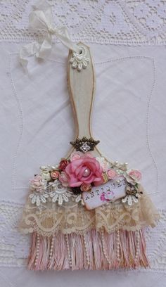 a piece of fabric with flowers and lace on it is hanging from a white doily