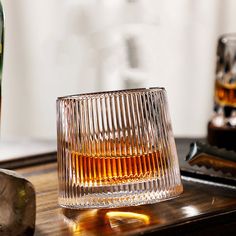 an empty glass sitting on top of a wooden table next to a bottle of alcohol