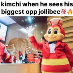 a cat standing next to a mascot in front of a tv screen with caption that reads, kimchi when he sees his biggest op jollibee