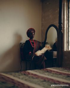 a woman sitting on a chair with a feather in her hand