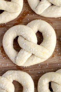 several pretzels are arranged on a cutting board with salt sprinkled around them