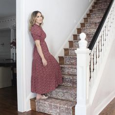 a woman in a red dress is standing on the stairs