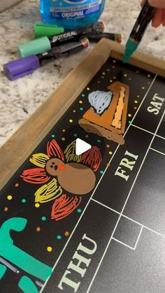 a close up of a child's hand writing on a blackboard with markers