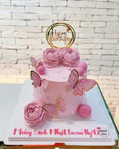 a pink birthday cake with butterflies on top