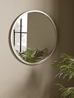 a mirror hanging on the wall next to a potted plant