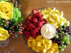 a platter filled with fruit, cheese and flowers