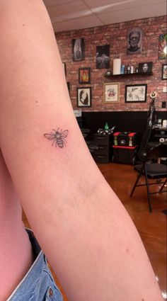 a woman's arm with a small bee tattoo on the back of her left arm