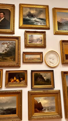 there are many paintings on the wall with a clock