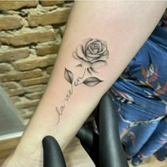 a woman's arm with a rose and the word love tattooed on her left forearm