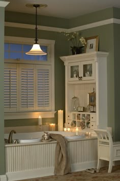 a white bath tub sitting under a window next to a shelf with candles on it