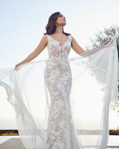 a woman in a wedding dress with her arms spread out and she is looking up