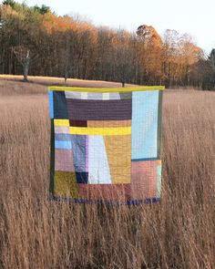 a patchwork quilt hanging in the middle of a field