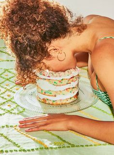 a woman leaning over a cake on top of a glass plate in front of her face