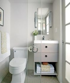 a white toilet sitting next to a sink in a bathroom under a mirror and framed pictures