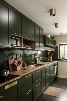 a kitchen with green cabinets and wooden counter tops, gold pulls on the door knobs