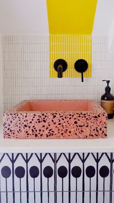 a bathroom with black and white tiles on the floor, yellow painting above the bathtub