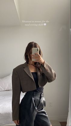 a woman taking a selfie with her cell phone in front of her face and wearing a brown blazer