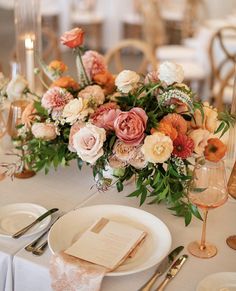 the table is set with white and pink flowers, silverware, and napkins