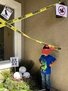 a young boy standing in front of a building with caution tape on his face and head