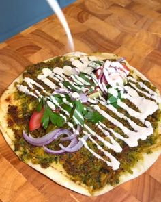 a pizza topped with onions, cheese and dressing on top of a wooden cutting board