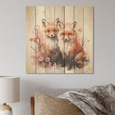 two red foxes sitting on top of a wooden wall