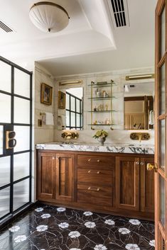 a bathroom with marble counter tops and wooden cabinets, along with glass doors leading to the shower