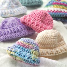 several crocheted hats sitting on top of a white blanket