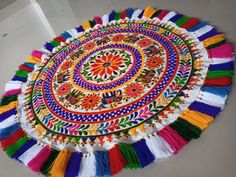 a multicolored round rug with tassels on the floor