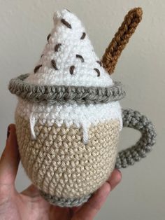 a crocheted coffee cup with an ice cream cone on top is held up to the camera