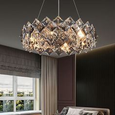 a modern chandelier hanging from the ceiling in a living room with large windows