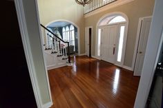 an open door leading to a foyer with hardwood flooring and chandelier hanging from the ceiling