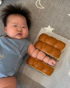 a baby laying on the floor next to some food