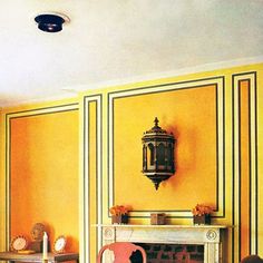 a living room with yellow walls and white trim on the fireplace mantel, chairs and table