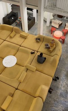 a living room filled with lots of yellow couches and tables covered in small pieces of furniture