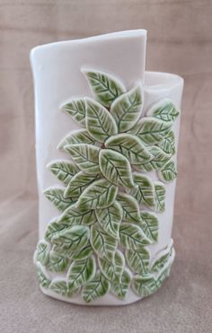 a white vase with green leaves on it