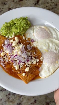 a white plate topped with eggs, meat and veggies on top of a table