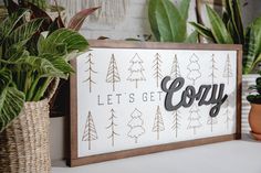 a wooden sign that says, let's get cozy next to potted plants