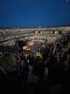 a large crowd at a concert with their hands up in the air and lights on